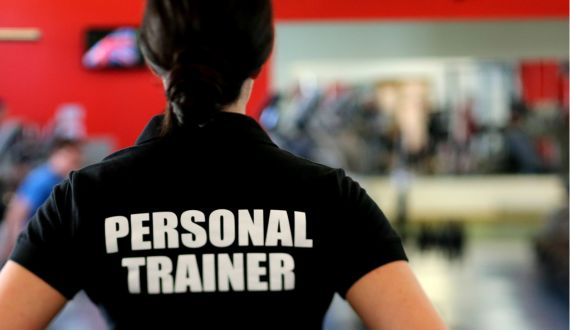 Rücken einer Frau mit schwarzem Shirt und Aufschrift Personal Trainer